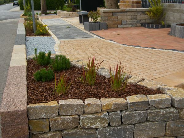 Steinmauer mit Pflanzen in einem Gartenweg.