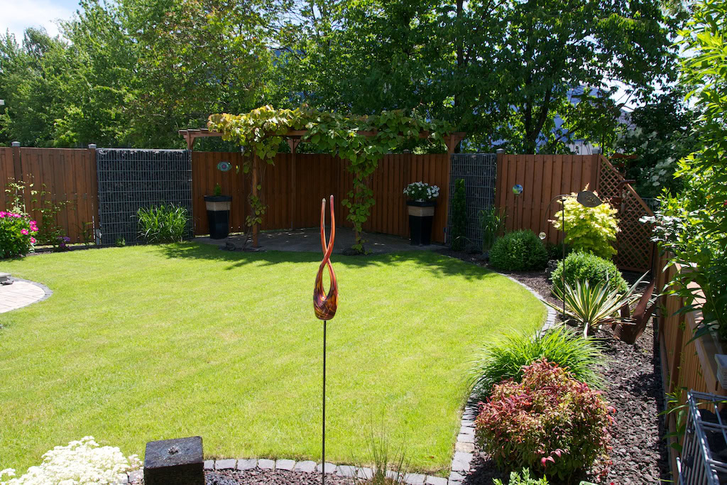 Gepflegter Garten mit Rasen und Holzlaube