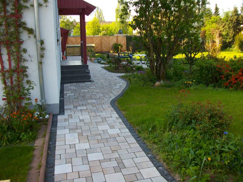 Gepflasterter Gartenweg mit Blumenbeeten