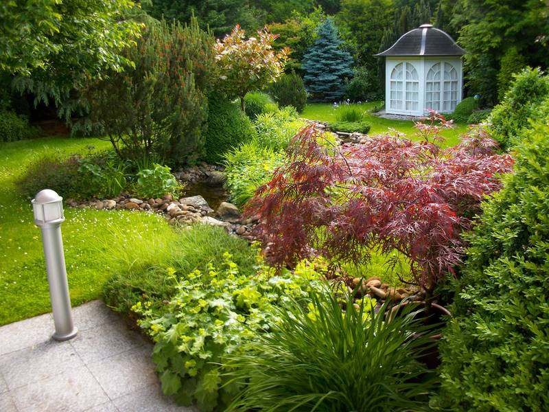 Grüner Garten mit Pavillon und Bachlauf