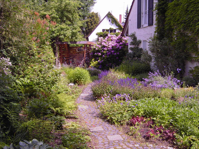 Blumenreicher Gartenweg vor einem Haus
