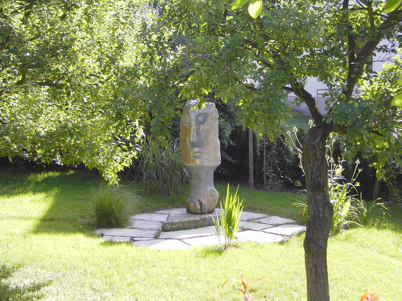Garten mit abstrakter Steinskulptur im Grünen