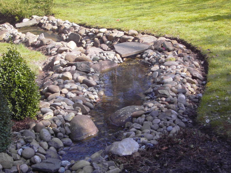 Kleiner Bachlauf mit Steinen im Garten