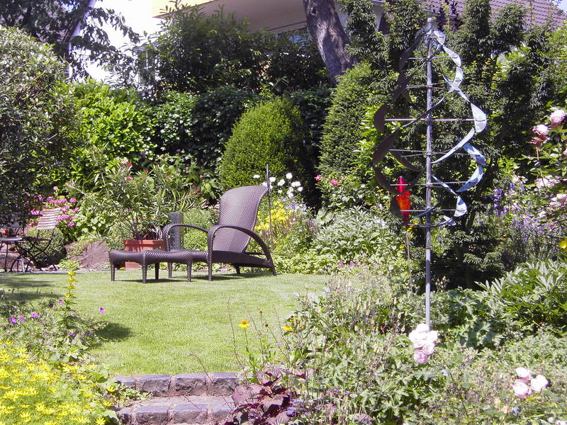 Garten mit Liegestuhl und Windspiel im Sommer